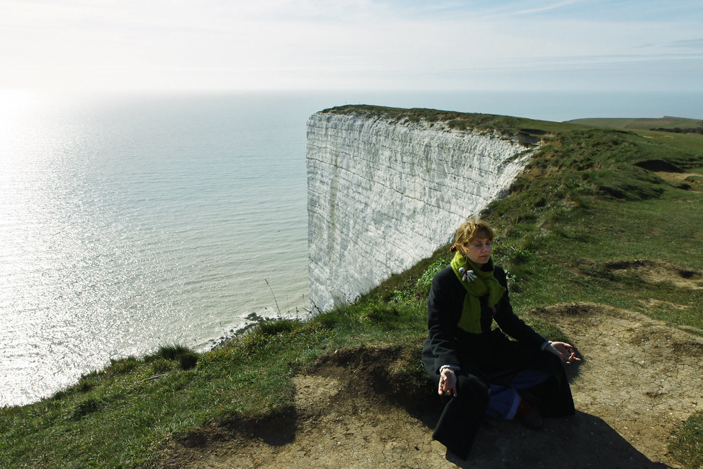 Person meditating on a clifftop overlooking the sea